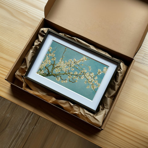 《杏花盛開》裝裱畫作的開箱情境，黑色相框搭配白卡紙，安放於牛皮紙箱內，襯以保護紙。