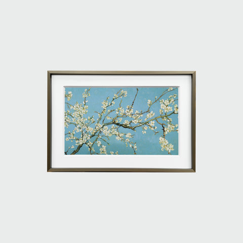 銅色細框裝裱的《杏花盛開》掛畫正面展示，展現藍天映襯的白色杏花之美。